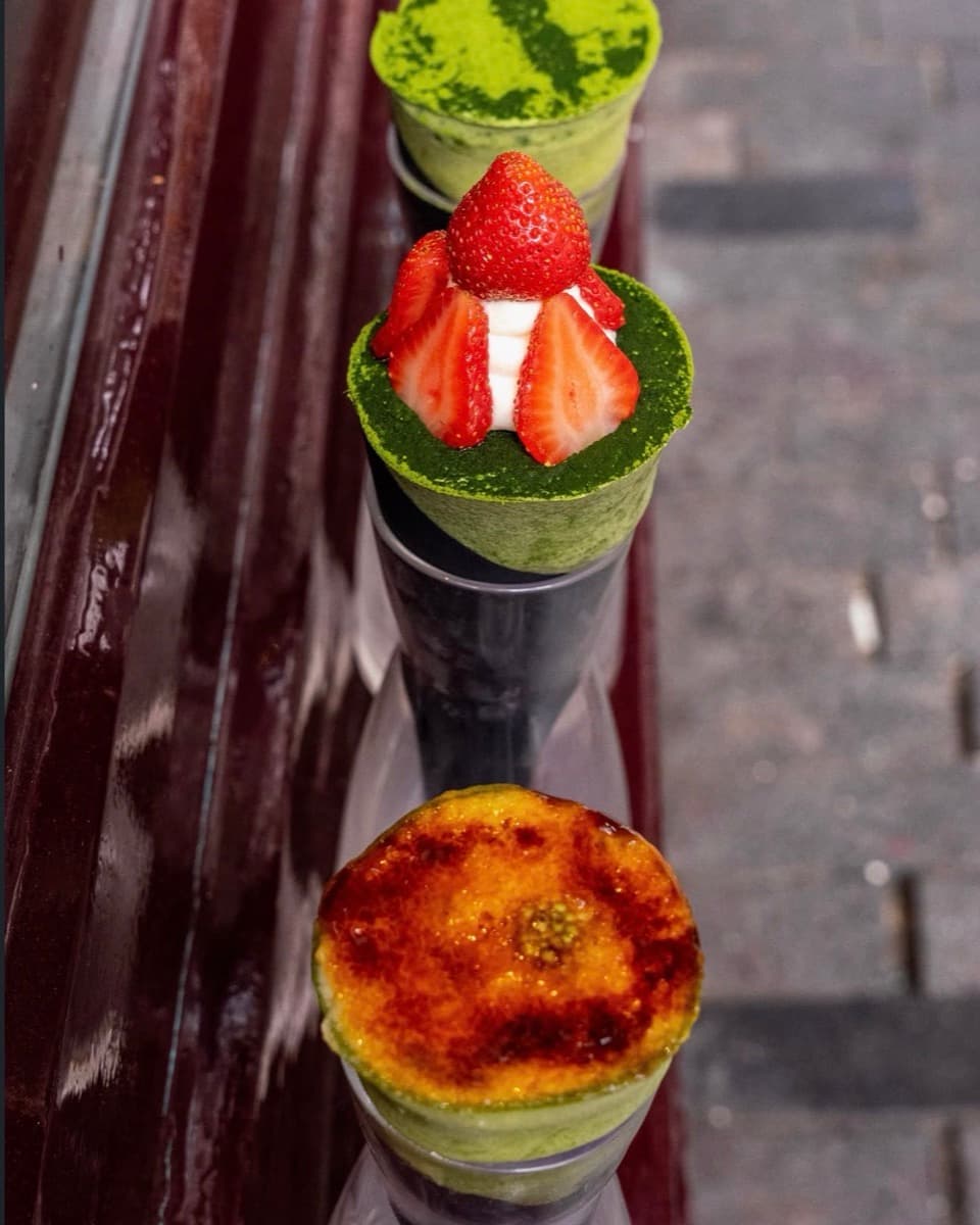 Three matcha dessert cones lined up on a shoot day — matcha powder, strawberries and cream, and a brûléed top